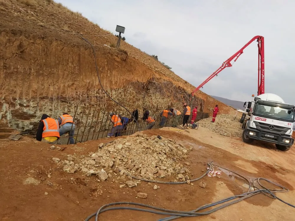 Concrete pump placing concrete on an embankment with the site team in attendance