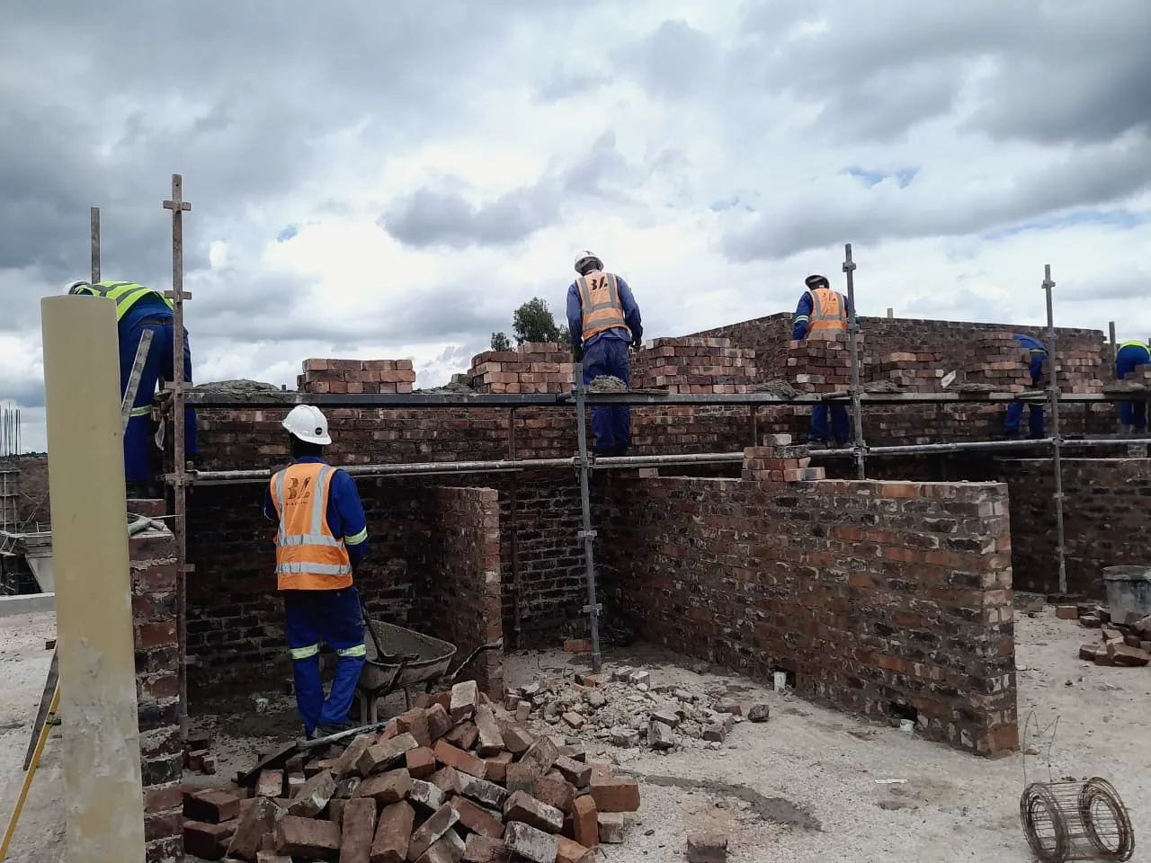 Bricklayers rebuilding damaged masonry walls on a property under restoration