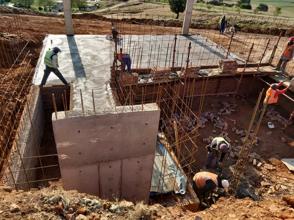 Site team placing concrete to a reinforced foundation and retaining structure
