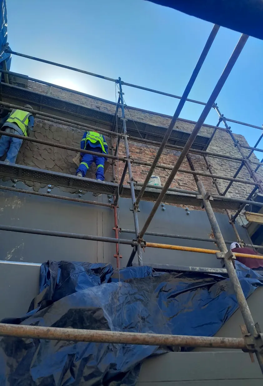 Tradesmen working from scaffolding on the exterior of a building during maintenance