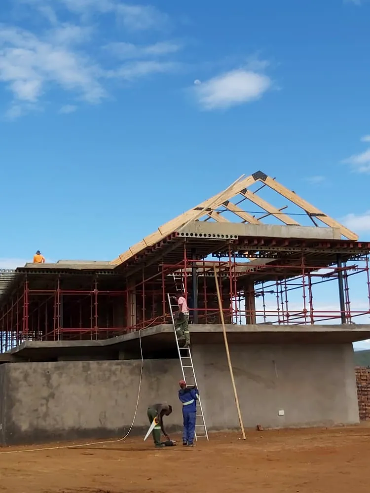 Timber roof trusses being installed by roofing tradesmen on a building under construction