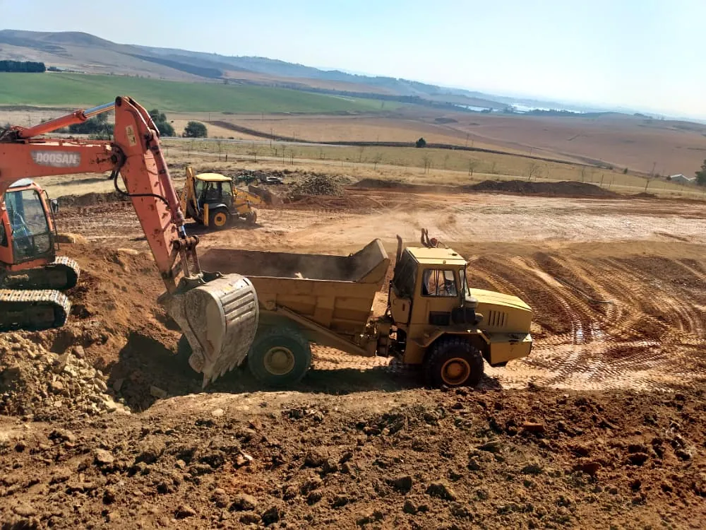Excavator and articulated dump truck carrying out bulk earthworks on site